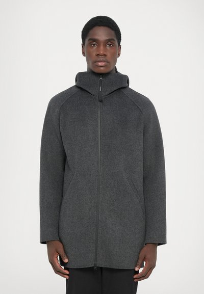 Manteau en laine gris foncé avec un col montant, des poches latérales et une fermeture éclair sur le devant. Dispose d'une coupe décontractée et d'un tissu texturé.