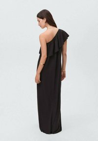 Abito maxi nero con un design asimmetrico a spalla unica, caratterizzato da un grande volantino lungo il colletto e una silhouette liscia e fluida.