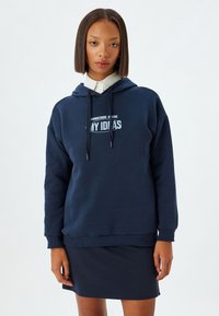 Sudadera con capucha azul marino en mezcla de algodón con dobladillo y puños de canalé; presenta el texto blanco "PENSANDO EN MIS IDEAS" en la parte frontal.