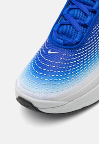 Αθλητικά παπούτσια τρεξίματος Nike με δίχτυ πλέγματος σε γαλάζια κλίμακα, διακοσμημένα με λευκές ραφές, λευκή ενδιάμεση σόλα και μαύρη καουτσούκ εξωτερική σόλα.