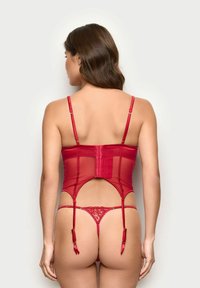 Ensemble de lingerie rouge avec un tissu transparent, des bretelles ajustables et des détails en dentelle. Le design du corset comporte une fermeture à crochets à l'arrière.