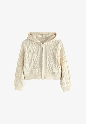 Zsinórrostélyú, krém színű kapucnis dzseki, elülső cipzárral, bordás aljjal és mandzsettával, melyen textúrált minták találhatók.