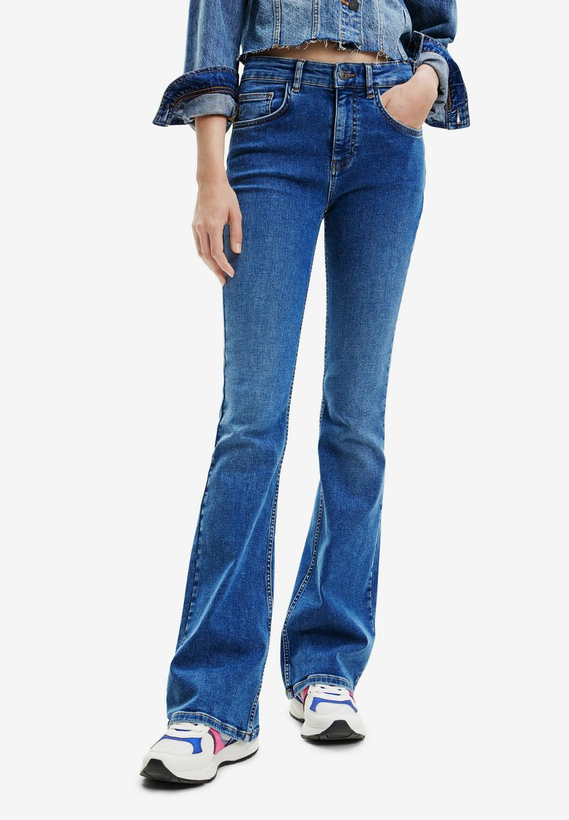 Blaue Schlagjeans aus Denim mit mittelhohem Bund, Fronttaschen und schmalem Schnitt über die Oberschenkel, endend mit einem leichten Schlag.