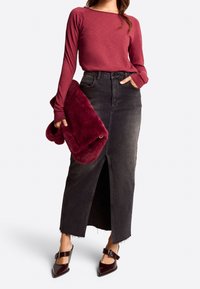 Bordowa bluzka z długim rękawem, czarna spódnica z denimu z wysokim stanem i przednim rozcięciem, ciemna torebka z futerkiem ekologicznego, błyszczące buty na obcasie z ostrym noskiem i klamrą.