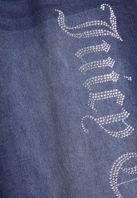 Σκούρο μπλε ύφασμα τζιν με διακοσμητικά στρας που σχηματίζουν ένα στυλιζαρισμένο κείμενο. Κοντινή λήψη της λείας υφής και των διακοσμήσεων.