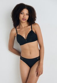 Svart undertøy sett med en bølgete blonde bralette med en liten sølvakcent og matchende bikini-bunn med blondekant detaljer.