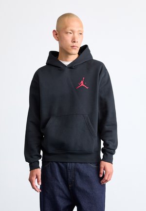 Fekete kapucnis sweatshirt pamut keverékből, kenguru zsebbel és piros Jordan logóval a mellkasán. Lazán illeszkedő szabás, bordás mandzsettákkal.