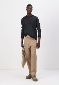 Maglione a fantasia navy, pantaloni khaki, scarpe beige e una borsa color tortora chiaro. Design semplice con lavorazione a maglia testurizzata e vestibilità rilassata.