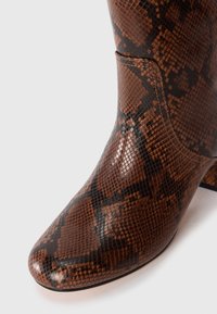 Brown and black snakeskin-patterned leather boot with a rounded toe and visible stitching on a white background.