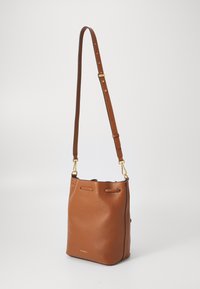 Borsa a secchiello in pelle marrone con tracolla regolabile, accessori in oro e superficie testurizzata; presenta una forma morbida e arrotondata e un design minimalista.