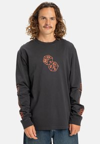 Dlouhý černý bavlněný rukávový tričko s oranžovým grafickým designem kostek na přední části a akcenty na rukávech. Klasický střih s kulatým výstřihem.