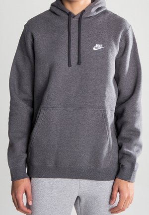 Sweat à capuche Nike gris foncé avec poche kangourou à l'avant et cordons, porté avec un pantalon de survêtement gris clair.