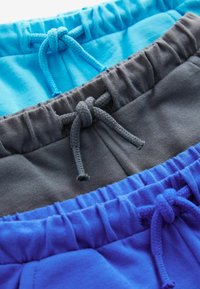 Trois paires de shorts en bleu clair, gris et bleu foncé. Chacun a une taille élastique avec des cordons de serrage assortis. Texture de tissu douce.