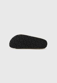 Svart gummisåle med bølgemønster; glatt, lysfarget materiale i kantene; avrundet form; minimalistisk design.