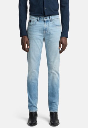 Light blue denim jeans with a slim fit, featuring faded details and five-pocket design. Paired with black ankle boots and a navy shirt.