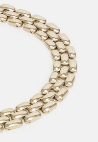 Gold-colored chunky chain necklace made of polished metal links, featuring a smooth, rounded design with connected pieces.