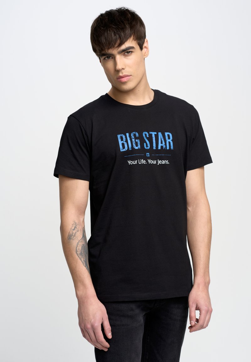 Camiseta de algodón negra con texto azul "BIG STAR" y el eslogan "Tu vida. Tus vaqueros." Manga corta y corte clásico.
