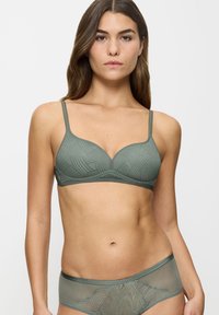 Reggiseno verde texturizzato con ferretto, dotato di sottili spalline regolabili e finitura liscia. Slip coordinato in tessuto trasparente con un delicato motivo.