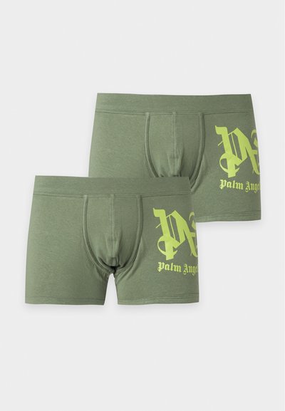 Deux boxers pour hommes vert olive avec un texte jaune de style gothique "Palm Angels" sur la cuisse gauche.