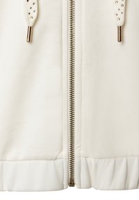 Weißer Reißverschlussjacke mit einem Metallreißverschluss, strukturierter Stoff und gerippten Bündchen. Verfügt über dekorative Kordeln mit Metallspitzen.