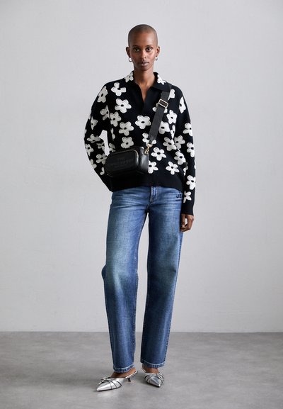 Sort sweater med hvid blomsterprint, blå lige ben jeans og sølv spidse sko. Sort crossbody taske med guld hardware.