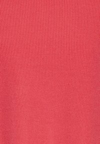 Gros plan sur un tissu tricoté rose corail montrant une texture fine côtelée en rangées régulières.