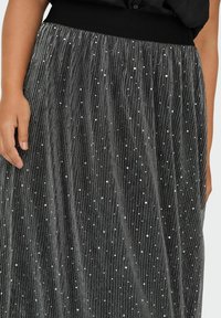 Falda negra plisada con una cinturilla ajustada y lentejuelas plateadas esparcidas sobre la tela texturizada.