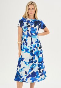 Korte mouw jurk met een getailleerde buste en een klokrok, met blauwe bloemenpatronen op een witte achtergrond, gemaakt van lichtgewicht stof.
