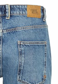Jeans dżinsowe o jasnoniebieskim odcieniu, z widocznymi szwami, skórzaną metką z napisem "camel active" oraz detalem na tylnej kieszeni.