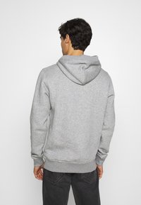Grauer Kapuzenpullover mit ribbelten Bündchen und Saum. Weicher Stoff, einfaches Design und keine sichtbaren Logos oder Muster.