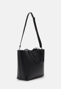 Sac fourre-tout en cuir noir avec une forme structurée, un fond plat, des poignées supérieures doubles et une longue bandoulière réglable. Texture lisse avec des accents minimaux.