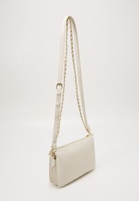 Vit fusk läder crossbody-väska med en strukturerad monogramdesign, försedd med ett guldkedjehandtag och justerbar rem. Dragkedjestängning och strömlinjeformad form.