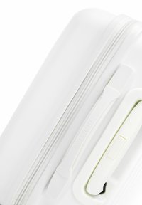 White hard-shell suitcase featuring a textured surface, smooth zipper closure, and a logo accent. Handle and zipper pull are also white.