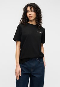 Μαύρο βαμβακερό t-shirt με κοντά μανίκια και στρογγυλή λαιμόκοψη. Διαθέτει διακριτικό λευκό λογότυπο «ALLSAINTS» στο αριστερό στήθος. Συνδυασμένο με σκούρο τζιν παντελόνι.