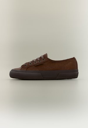 Sneaker marrone in camoscio basso con suola in gomma scura e lacci, mostrato di profilo su uno sfondo beige uniforme.
