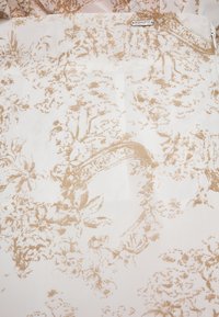 Blumenmusterstoff in Beige und Creme mit filigranen Designs von Blumen und Blättern. Weiche Textur mit einem leichten, luftigen Erscheinungsbild.