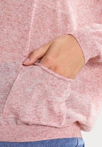 Ljusrosa strukturerad tröja med ficka och ribbade muddar, med ett mjukt, melerat tyg och en avslappnad passform.