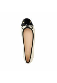Ballerines avec un corps en tissu crème, un bout en vernis noir et des bords noirs. Présente un nœud décoratif noir et des accents en métal doré.