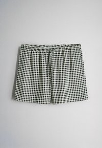 Schwarz-weiß karierten Shorts mit elastischem Bund und Frontknoten, flach auf einer schlichten hellen Fläche ausgelegt.