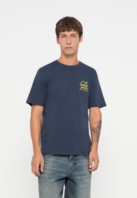 Marineblå bomulds T-shirt med korte ærmer, med en gul "Tranquil Waters" grafik på brystet. Klassisk crew neck design.