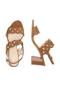 Sandale cu toc din suede bej, cu un design geometric decupat, vârful deschis, curea la glezna și toc pătrat. Dispune de accesorii din aur pentru închidere.