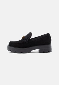 Mustad nahast loafersid, millel on paks kummist tallad, kuldse riistvaraga aksent esiosas ja pehme vooder, mis on nähtav avauses.