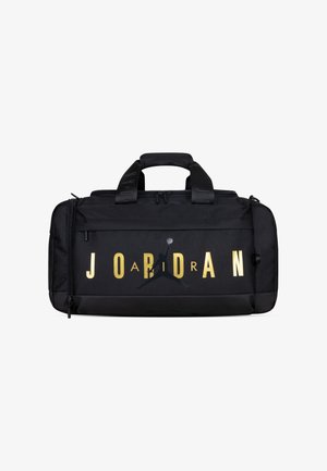 Črna torba za šport s zlatim napisom "JORDAN", s logotipom Jumpman. Narejena iz trpežne tkanine z dvema ročajema in zadrgo.