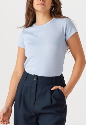 Lichtblauwe geribbelde t-shirt met korte mouwen en een ronde hals, voorzien van een subtiele logo op de borst, gecombineerd met donkerblauwe broek.