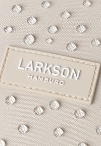 Beige fabric with raised, reflective dots. Features a cream-colored rectangular label with "LARKSON HAMBURG" in white lettering.