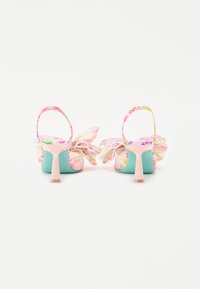 Sandales à talons colorées avec un motif floral rose clair, base aqua, et un accent de fleur proéminent à l'arrière. Brides de cheville ajustables.