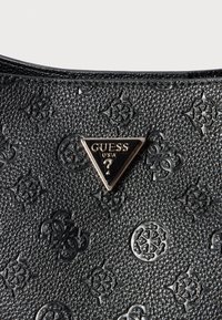 Black textured handbag featuring embossed designs, a triangular metal logo in the center, and a smooth zipper top.
