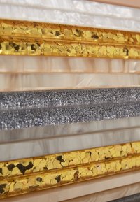 Layered materials include gold hexagonal foil, silver glitter, translucent beige, and creamy textured surfaces, showcasing various colors and finishes.