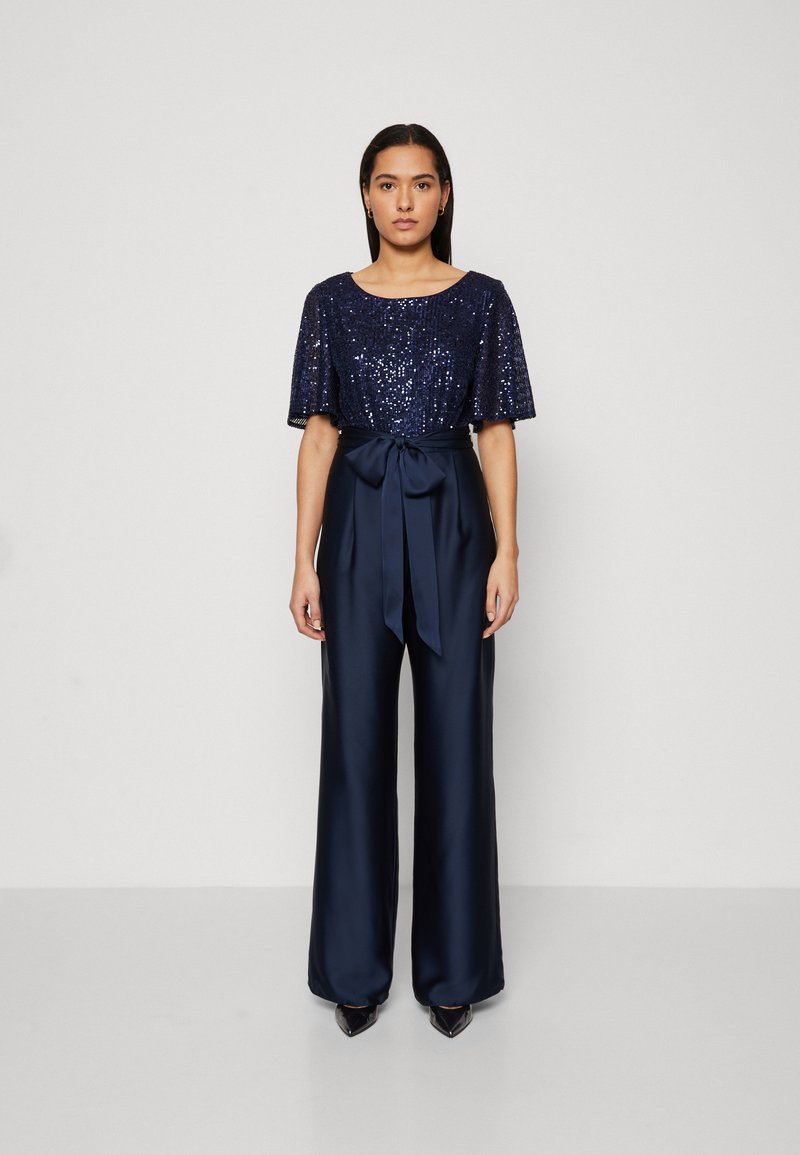 Mørkeblå jumpsuit med brede ben, med en dekorert kortermet topp og satengbånd i midjen. Glatt tekstur og skreddersydd passform.