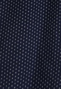 Granatowy materiał korkowy z wzorem siatki z małymi białymi krzyżykami, z pionowymi żeberkami dodającymi tekstury.